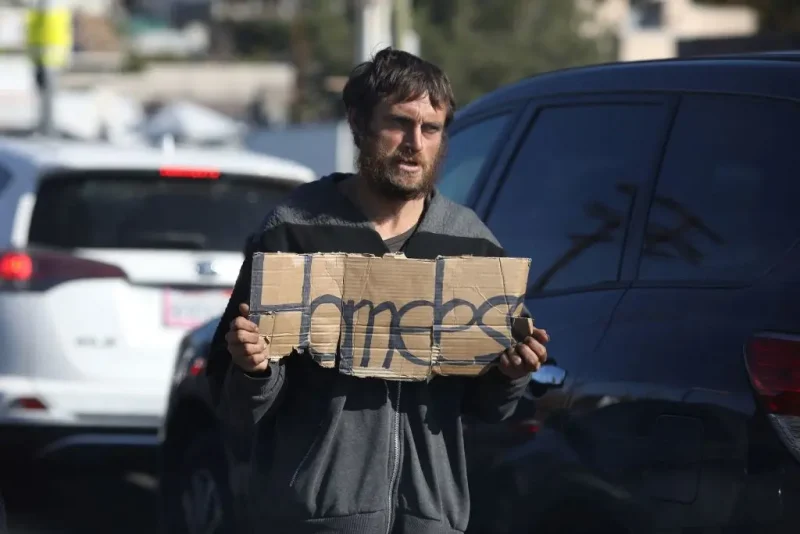 An unhoused person holds a sign reading "Homeless" as they solicits for money in traffic on Glendale boulevard in Los Angeles, California, December 19, 2022. - A state of emergency over spiraling levels of homelessness was declared in Los Angeles on Monday as the new mayor pledged a "seismic shift" for one of the most intractable problems in America's second biggest city. Tens of thousands of people sleep rough on Los Angeles streets every night, in an epidemic that shocks many visitors to one of the wealthiest urban areas on the planet. (Photo by DAVID SWANSON / AFP) (Photo by DAVID SWANSON/AFP via Getty Images)