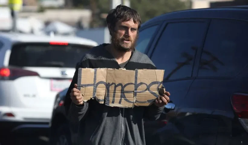 An unhoused person holds a sign reading "Homeless" as they solicits for money in traffic on Glendale boulevard in Los Angeles, California, December 19, 2022. - A state of emergency over spiraling levels of homelessness was declared in Los Angeles on Monday as the new mayor pledged a "seismic shift" for one of the most intractable problems in America's second biggest city. Tens of thousands of people sleep rough on Los Angeles streets every night, in an epidemic that shocks many visitors to one of the wealthiest urban areas on the planet. (Photo by DAVID SWANSON / AFP) (Photo by DAVID SWANSON/AFP via Getty Images)