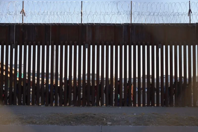 TOPSHOT - Migrants line up to be processed by US Border Patrol under the Stanton St. Bridge after entering the US in El Paso, Texas, on December 21, 2022. - The US Supreme Court halted December 19, 2022 the imminent scrapping of a key policy used since Donald Trump's administration to block migrants at the southwest border, amid worries over a surge in undocumented immigrants. An order signed by Chief Justice John Roberts placed an emergency stay on the removal planned for December 21, 2022 of Title 42, which allowed the government to use Covid-19 safety protocols to summarily block the entry of millions of migrants. (Photo by Allison Dinner / AFP) (Photo by ALLISON DINNER/AFP via Getty Images)