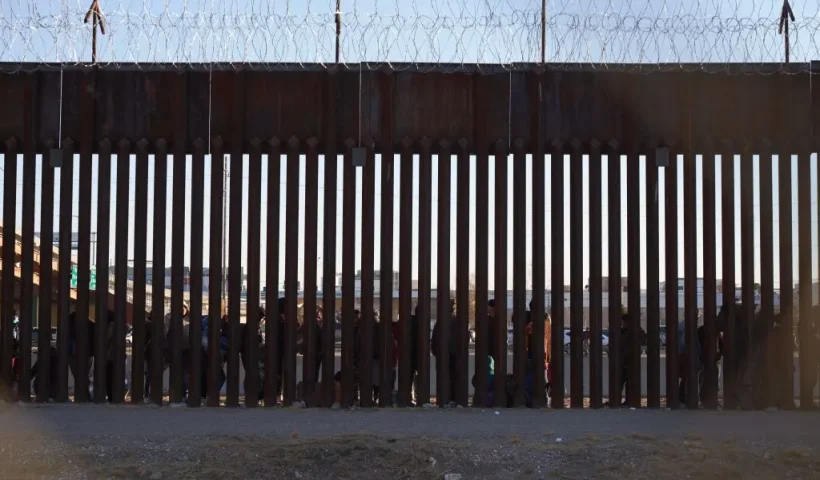 TOPSHOT - Migrants line up to be processed by US Border Patrol under the Stanton St. Bridge after entering the US in El Paso, Texas, on December 21, 2022. - The US Supreme Court halted December 19, 2022 the imminent scrapping of a key policy used since Donald Trump's administration to block migrants at the southwest border, amid worries over a surge in undocumented immigrants. An order signed by Chief Justice John Roberts placed an emergency stay on the removal planned for December 21, 2022 of Title 42, which allowed the government to use Covid-19 safety protocols to summarily block the entry of millions of migrants. (Photo by Allison Dinner / AFP) (Photo by ALLISON DINNER/AFP via Getty Images)