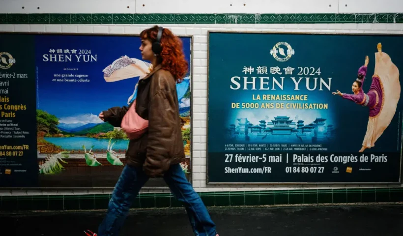 This photograph taken on March 1, 2024, shows a woman walking past posters of the Shen Yun dance show in a metro station in Paris. Dancers dressed in colourful costumes gracefully twirl in front of digitised landscapes of China, with an ambiguous message in the background: since 2006, the Chinese-American company Shen Yun, currently on tour in France, has used its grandiose shows to spread vehement criticism of Beijing and conservative rhetoric around the world. (Photo by Dimitar DILKOFF / AFP) (Photo by DIMITAR DILKOFF/AFP via Getty Images)