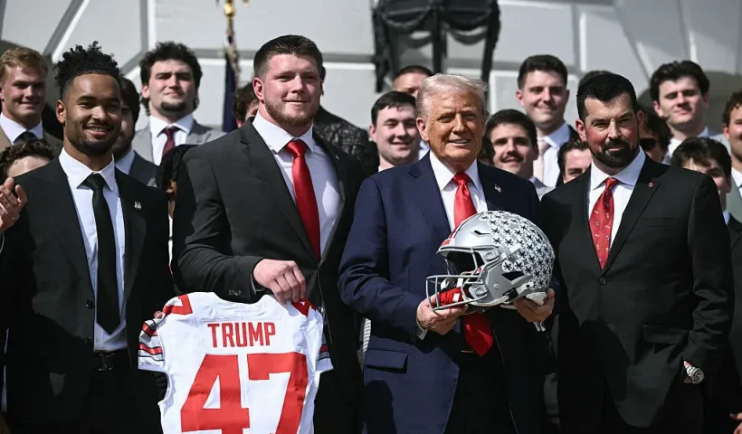 US President Donald Trump, alongside defensive end Jack Sawyer (2nd L), wide receiever Emeka Egbuka (L), and head coach Ryan Day (R), holds an Ohio State Buckeyes football helmet as he hosts the 2025 College Football National Champions, Ohio State Buckeyes, celebrating the team's title-winning season with a ceremony on the South Lawn of the White House in Washington, DC, April 14, 2025. (Photo by Brendan SMIALOWSKI / AFP) (Photo by BRENDAN SMIALOWSKI/AFP via Getty Images)