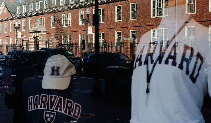 CAMBRIDGE, MASSACHUSETTS - APRIL 17: Harvard University is reflected in the window of a merchandise store across the street from the school on April 17, 2025 in Cambridge, Massachusetts. The Trump administration announced that it would block Harvard University from receiving $2.2 billion in federal grants and $60 million in contracts after the school refused demands to adopt new policies relating to student and faculty conduct, admissions, anti-semitism on campus and DEI. (Photo by Sophie Park/Getty Images)