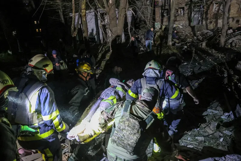 TOPSHOT - Ukrainian rescuers carry a wounded local resident as they operate at the site of a Russian missile attack in Kyiv early on April 24, 2025, amid the Russian invasion of Ukraine. A "massive" Russian missile attack on Kyiv on April 24, 2025, killed at least nine and wounded dozens in one of the deadliest strikes on the Ukrainian capital since Moscow launched its invasion more than three years ago. (Photo by STRINGER / AFP) (Photo by STRINGER/AFP via Getty Images)