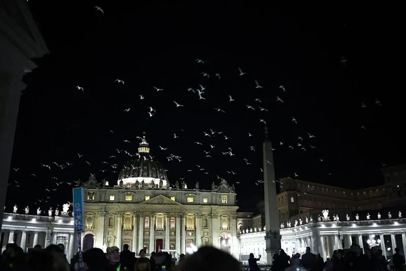A flock of birds fly over visitors and mourners queueing to access St Peter's Basilica to pay their respects to the late Pope Francis, in The Vatican on April 24, 2025. The Vatican on April 24 said some 61,000 people had already paid their respects to Pope Francis, whose body is lying in state in St Peter's Basilica ahead of his funeral. (Photo by HENRY NICHOLLS / AFP) (Photo by HENRY NICHOLLS/AFP via Getty Images)