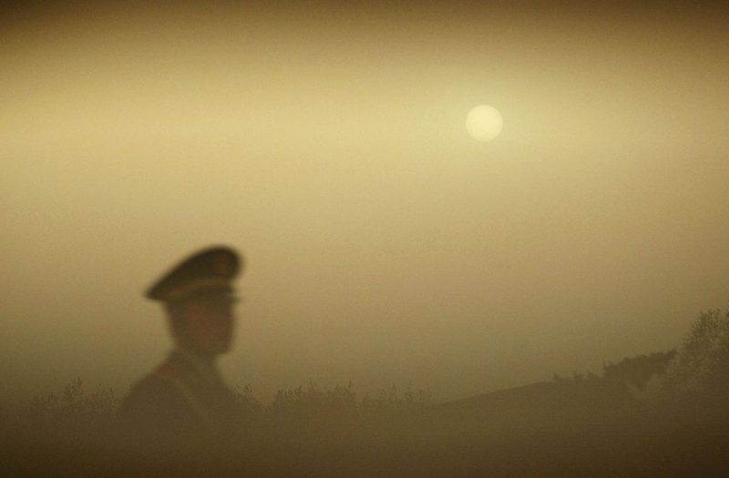 BEIJING, CHINA - APRIL 18: (CHINA OUT) A police officer patrols Tiananmen Square during a dust storm on April 18, 2006 in Beijing, China. A sandstorm hitting the China-Mongolia border on April 15 started to affect Beijing at midnight on April 16. The China Meteorological Administration (CMA) announced at a press conference that the sandstorm had dropped about 330,000 tons of dust on Beijing. According to forecasts, northern China will experience three sand storms between April 18 and 27.(Photo by China Photos/Getty Images)