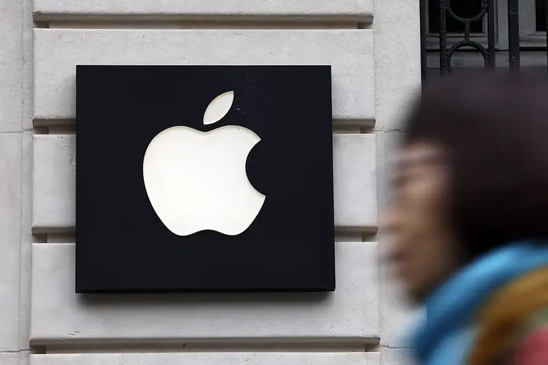 A woman walks past an Apple logo at an Apple store in Paris, France, April 23, 2025. REUTERS/Abdul Saboor