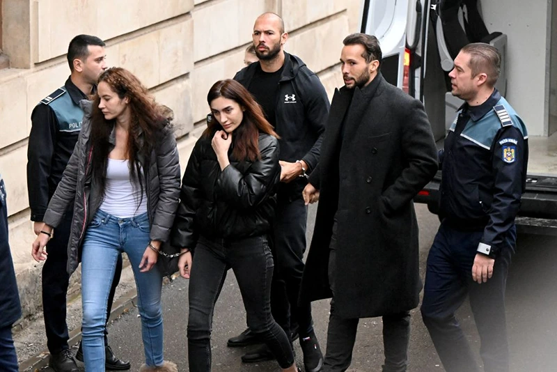 British-US former professional kickboxer and controversial influencer Andrew Tate (3rd R), his brother Tristan Tate (2nd R), and two unidentified Romanian women, arrive handcuffed and escorted by police at a courthouse in Bucharest on January 10, 2023 for a court hearing on their appeal against pre-trial detention for alleged human trafficking, rape and forming a criminal group. (Photo by Daniel MIHAILESCU / AFP) (Photo by DANIEL MIHAILESCU/AFP via Getty Images)