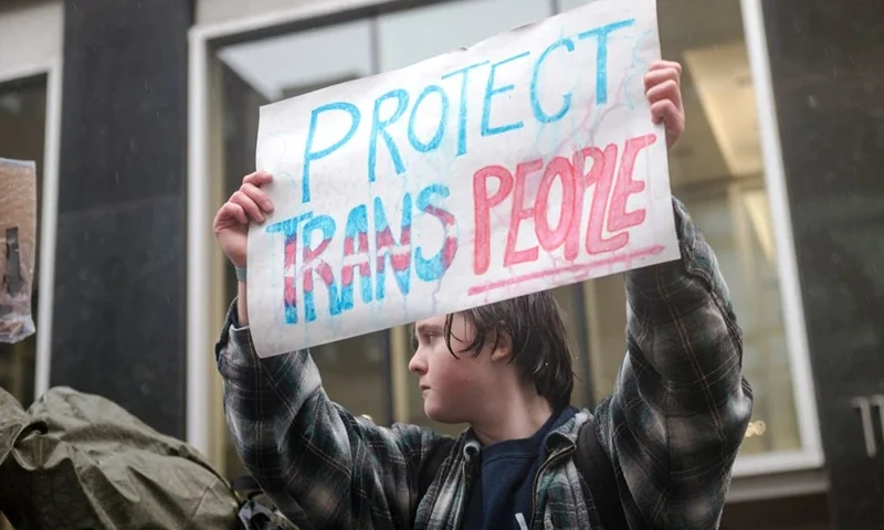 A person holds a sign reading "Protect Trans People" as LGBTQ activists protest on March 17, 2023, in front of the US Consulate in Montreal, Canada, calling for transgender and non-binary people be admitted into Canada. - According to police services, some 200 people gathered in the rain to show support for the trans community in the United States. (Photo by ANDREJ IVANOV / AFP) (Photo by ANDREJ IVANOV/AFP via Getty Images)