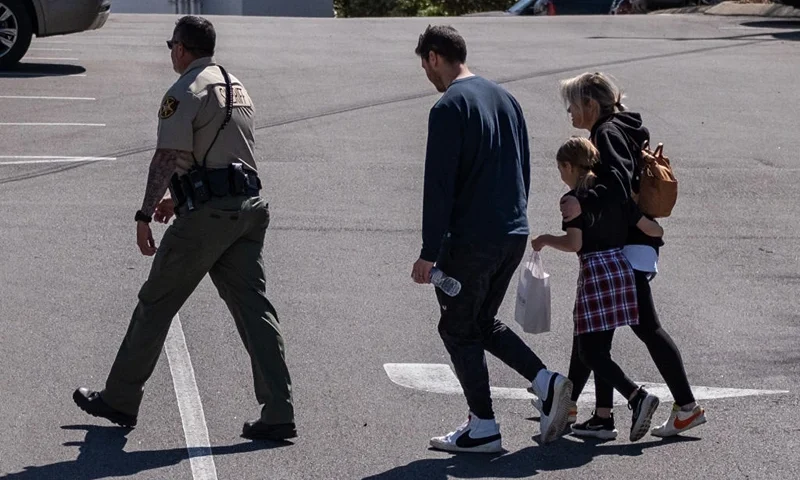 NASHVILLE, TN - MARCH 27: A law enforcement officer escorts a family from Woodmont Baptist Church where children were reunited with their families after a mass shooting at The Covenant School on March 27, 2023 in Nashville, Tennessee. According to initial reports, three students and three adults were killed by the shooter, a 28-year-old woman. The shooter was killed by police responding to the scene. (Photo by Seth Herald/Getty Images)
