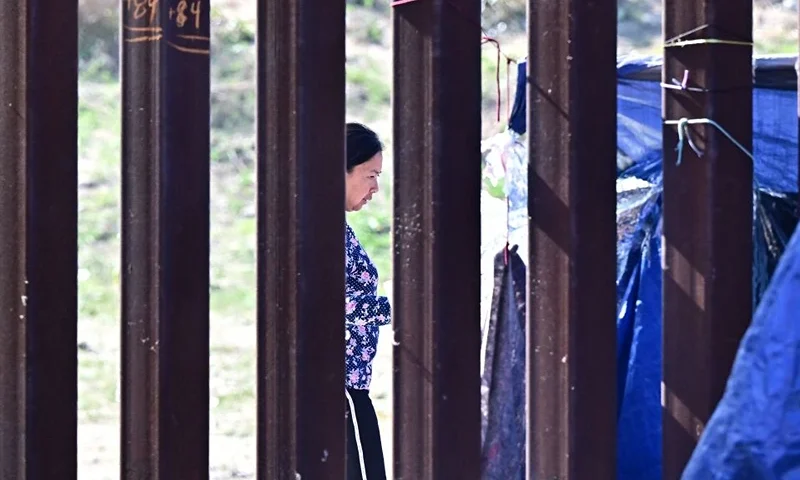 Migrants take shelter under blue tarps at the US-Mexico border in San Diego, California on October 10, 2023. More than 200,000 migrants have crossed the San Diego sector of the US-Mexico border this year from January to August, the highest number in two decades. (Photo by Frederic J. BROWN / AFP) (Photo by FREDERIC J. BROWN/AFP via Getty Images)