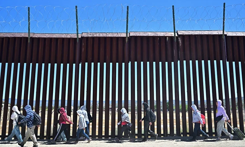 OPSHOT - Migrants walk on the US side of the border wall in Jacumba Hot Springs, California on June 5, 2024, after crossing from Mexico. Migrants from countries such as Turkey, Jordan, Guatemala, Nicaragua, China and India made their way on foot into the United States today before being met with by Customs and Border Patrol agents for processing. The United States will temporarily close its Mexico border to asylum seekers starting today, June 5, as President Joe Biden as tries to neutralize his political weakness on migration ahead of November's election battle with Donald Trump. The 81-year-old Democrat signed a long-awaited executive order taking effect at midnight to "gain control" of the southern frontier with Mexico, after record numbers of illegal border crossings sparked concerns among voters. (Photo by Frederic J. BROWN / AFP) (Photo by FREDERIC J. BROWN/AFP via Getty Images)