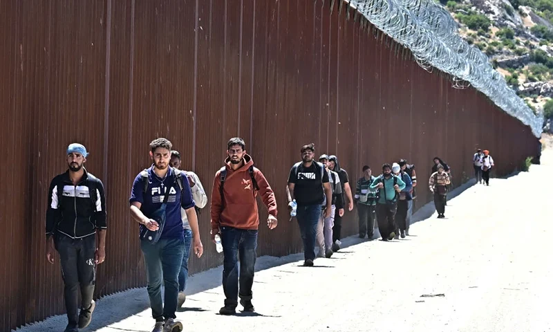 Migrants walk on the US side of the border wall in Jacumba Hot Springs, California on June 5, 2024, after walking across from Mexico. (Photo by Frederic J. BROWN / AFP) (Photo by FREDERIC J. BROWN/AFP via Getty Images)