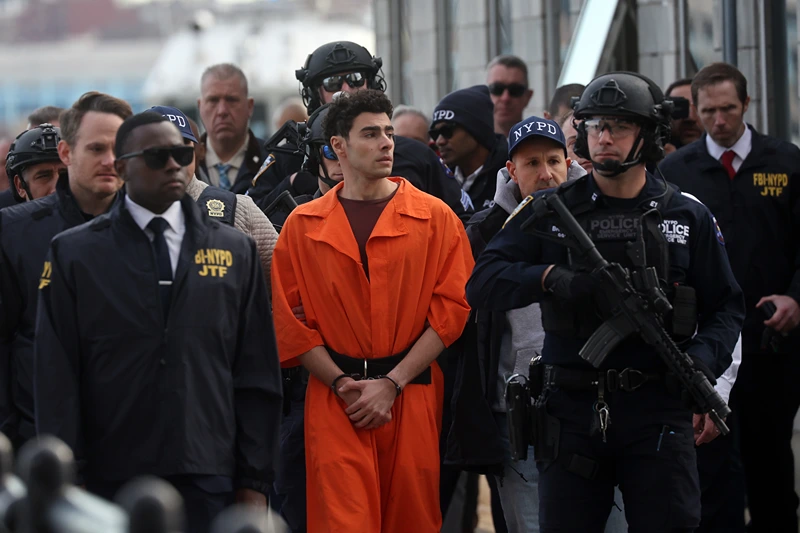 NEW YORK, NEW YORK - DECEMBER 19: Luigi Mangione, suspect in the killing of UnitedHealthcare CEO Brian Thompson in New York City, arrives at a heliport with members of the NYPD on December 19, 2024 in New York City. The 26-year-old was arrested in Pennsylvania on December 9 after being spotted at a McDonald's in Altoona amid a national manhunt. Mangione also appeared in a Pennsylvania court on forgery and firearms charges today, where he waived extradition to New York after being indicted on 11 charges including first-degree murder in furtherance of terrorism. (Photo by Spencer Platt/Getty Images)