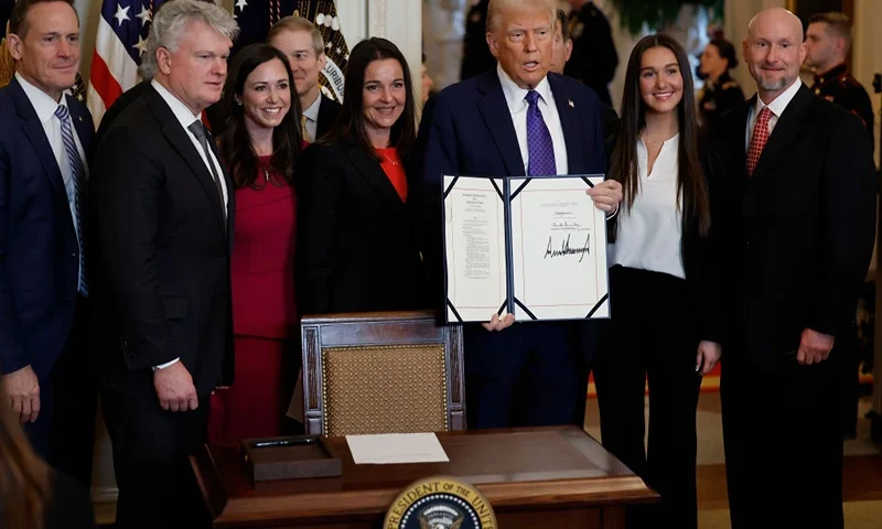 WASHINGTON, DC - JANUARY 29: Surrounded by members of Congress and the family of Laken Riley, U.S. President Donald Trump poses with the signed Laken Riley Act, the first piece of legislation passed during his second term in office, in the East Room of the White House on January 29, 2025 in Washington, DC. Jason Riley and Allyson Philips, the parents of 22-year-old Laken Riley, a University of Georgia nursing student who was murdered in 2024 by an undocumented immigrant, attended the signing ceremony. Among other measures, the law directs law enforcement authorities to detain and deport immigrants who are accused but not yet convicted of specific crimes, if they are in the country illegally. (Photo by Chip Somodevilla/Getty Images)