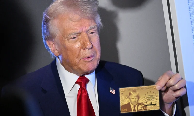US President Donald Trump holds the $5 million dollar Gold Card as he speaks to reporters while in flight on board Air Force One, en route to Miami, Florida on April 3, 2025. Trump is travelling to the Trump National Doral Golf Club before going to his Mar-a-Lago Resort. (Photo by MANDEL NGAN / AFP) (Photo by MANDEL NGAN/AFP via Getty Images)