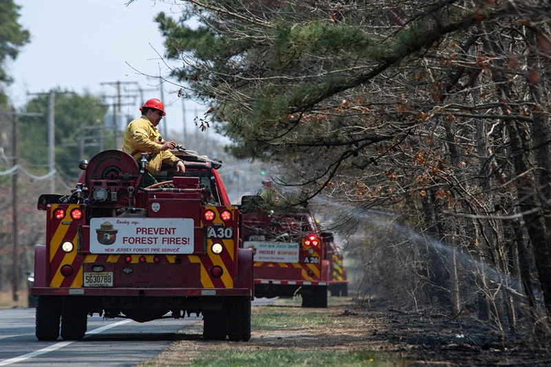 New Jersey Forest Fire Service fire crews work to extinguish the Jones Road Fire near Lacey Township in Ocean County, New Jersey, on April 23, 2025. Some 3,000 residents were evacuated in the US state of New Jersey after a wildfire exploded in size, scorching thousands of acres and threatening hundreds of structures, the state's fire service said on April 22. New Jersey had been under an official drought warning, the state's Department of Environmental Protection said in March. (Photo by Matthew Hatcher / AFP) (Photo by MATTHEW HATCHER/AFP via Getty Images)