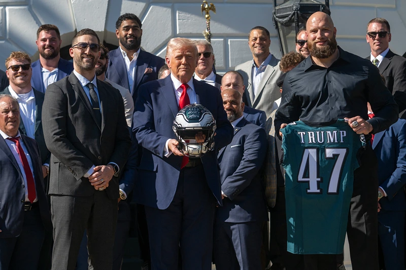 TOPSHOT - US President Donald Trump holds up a helmet, flanked by Philadelphia Eagles' tackle #65 Lane Johnson (R) and Philadelphia Eagles head coach Nick Sirianni (L), as he hosts an event celebrating the Philadelphia Eagles, 2025 Super Bowl champions, at the White House on April 28, 2025, in Washington, DC. The Eagles defeated the defending champion Kansas City Chiefs 40-22 in Super Bowl LIX, held in New Orleans, Louisiana on February 9, 2025. (Photo by Jim WATSON / AFP) (Photo by JIM WATSON/AFP via Getty Images)