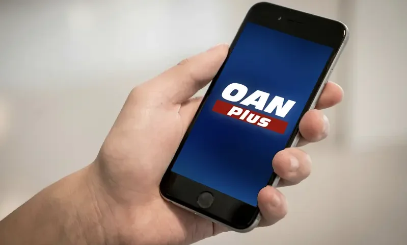 Hand holding a phone that shows the OAN Plus logo.