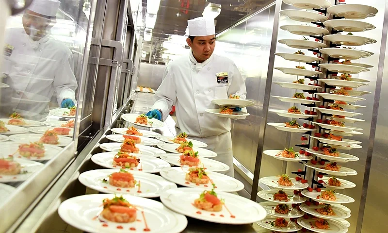 A chef prepares food in the galley of the Cunard cruise liner RMS Queen Mary 2 sailing in the Atlantic ocean during the Bridge 2017, a transatlantic race between the cruise liner and the world's fastest Ultim trimarans from Saint-Nazaire, France, to New York City, USA on June 27, 2017. / AFP PHOTO / LOIC VENANCE (Photo by LOIC VENANCE/AFP via Getty Images)