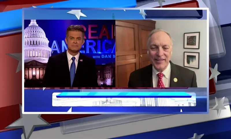 Video still from Real America on One America News Network showing a split screen of the host on the left side, and on the right side is the guest, Rep. Andy Biggs.