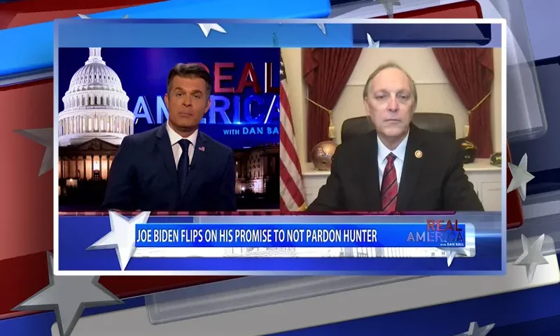 Video still from Real America on One America News Network showing a split screen of the host on the left side, and on the right side is the guest, Rep. Andy Biggs.