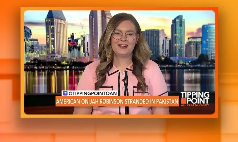 Video still of the host of Tipping Point at the desk of their talk show on One America News Network.