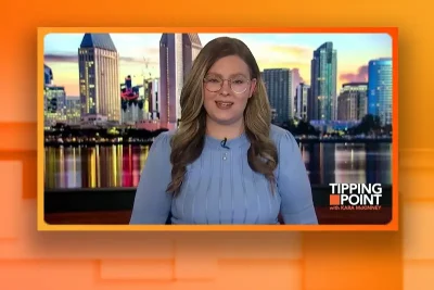 Video still of the host of Tipping Point at the desk of their talk show on One America News Network.