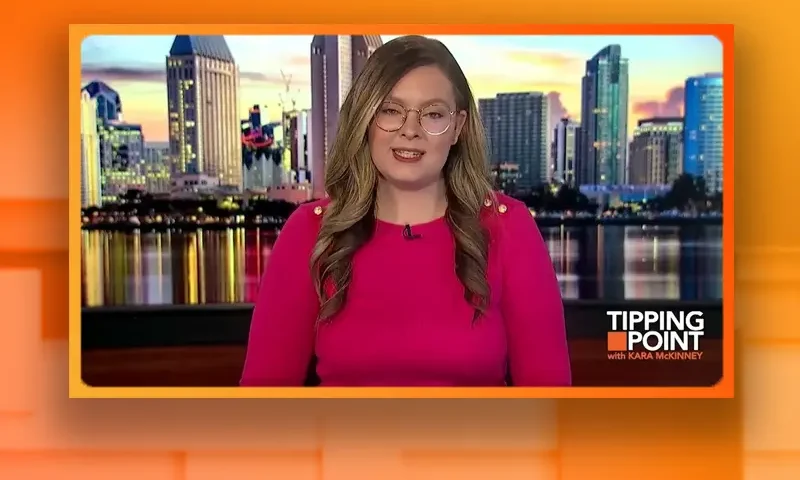 Video still of the host of Tipping Point at the desk of their talk show on One America News Network.